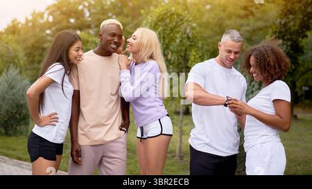 Amis adolescents de groupe multiethnique. Afro-américain asiatique étudiant de race blanche passer du temps ensemble amitié multiraciale heureux souriant personnes vêtues noir blanc sportswear réunion en extérieur Banque D'Images