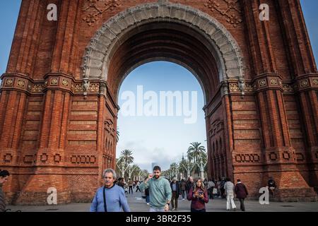 BARCELONE, ESPAGNE - 12 AVRIL 2025 : les visiteurs marchent sous l'Arc de Triomf en briques à Barcelone, Espagne, en passant par l'arc mudéjar vers la ligne des palmiers Banque D'Images
