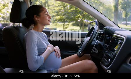 Heureuse enceinte africaine-américaine femme santé femme fille voiture future voiture mère véhicule de transport conduire la grossesse automobile touchant le ventre caressant Banque D'Images