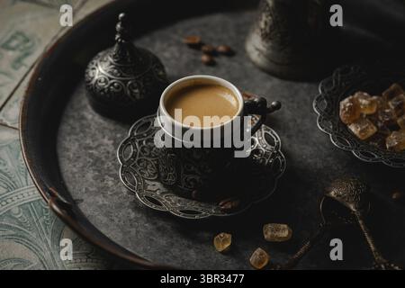 Café dans une tasse traditionnelle turque en métal et grains de café sur fond de carrelage Banque D'Images