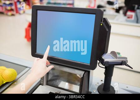 Image rognée d'une personne touchant l'écran du lecteur de codes-barres Banque D'Images