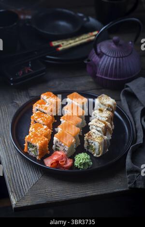 Différents types de rouleaux de sushi servi sur la plaque noire sur fond sombre Banque D'Images