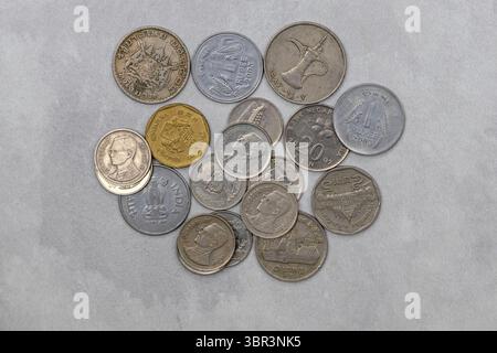 Collection de vieilles pièces internationales dispersées sur une surface. Monnaie vintage d'Inde, Thaïlande, Singapour, Malaisie et les Émirats arabes Unis Banque D'Images