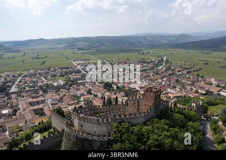 Vue aérienne de l'imposante forteresse Castello Scaligero, avec ses anciens murs de pierre, surplombe la ville au milieu du paysage verdoyant, Castello Scaligero, Vénétie, Italie. Banque D'Images