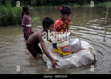 13 juillet 2020 : 13 juillet 2020 : des enfants vus ramasser de l'eau potable, se déplaçant sur une route inondée sur un radeau à la main en plastique dans l'eau de crue à Sadarpar, région d'Uposhahar en raison de la montée de l'eau en amont et de fortes précipitations déclenchées par la mousson au cours des derniers jours à Sylhet. (Crédit image : © MD Rafayat Haque Khan/ZUMA Wire) Banque D'Images