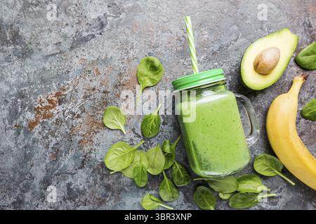 Smoothie vert sain avec épinards, avocat, banane et graines de chia dans des pots en verre sur fond de pierre grise, vue de dessus Banque D'Images