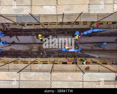 Vue aérienne de travailleurs de la construction dans des équipements de sécurité vibrants travaillant au milieu de l'acier et du béton, une symphonie d'effort humain façonnant le paysage urbain, Lagos, Lagos, Nigeria. Banque D'Images