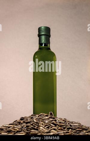 Une bouteille en verre avec de l'huile de tournesol se trouve dans un tas de graines Banque D'Images