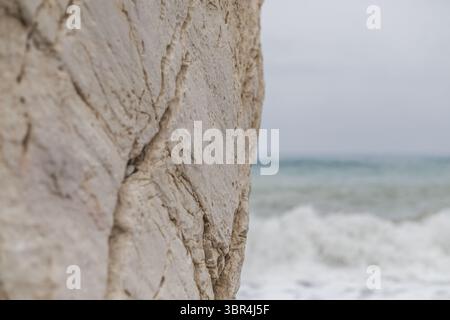 La vue sur la formation rocheuse rugueuse de couleur crème contraste avec les vagues turquoises qui s'écrasent sur le rivage sous un ciel doux et couvert, Paphos, Paphos, Chypre. Banque D'Images