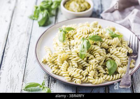 Fusillis italien avec de la sauce pesto fait maison sur une plaque sur fond de bois blanc Banque D'Images