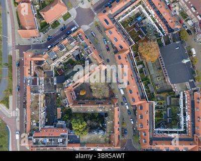 Vue aérienne de confortables bâtiments au toit rouge projetant des ombres géométriques sur des rues tranquilles et des cours cachées, Amsterdam, Hollande du Nord, pays-Bas. Banque D'Images