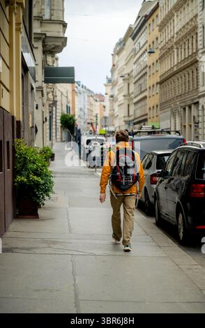 Homme avec sac à dos marchant le long de la rue de la ville à Vienne Banque D'Images