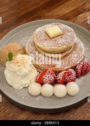 Délicieuses crêpes servies dans une assiette, avec beurre, glace, fraises et boulettes de riz gluantes. Banque D'Images