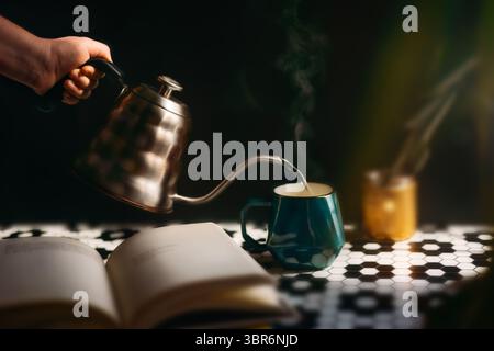 Main versant le thé avec de la vapeur à la lumière du soleil Banque D'Images