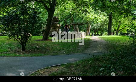 Londres - 06 21 2022 : femme assise sur un tronc d'arbre à Westfield Park Banque D'Images