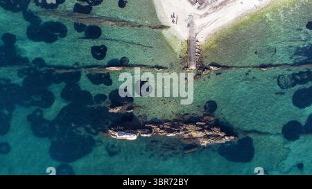 Vue aérienne de la côte accidentée rencontrant les eaux turquoises claires, révélant des roches submergées et des textures contrastées, Split, comté de Split-Dalmatie, Croatie. Banque D'Images