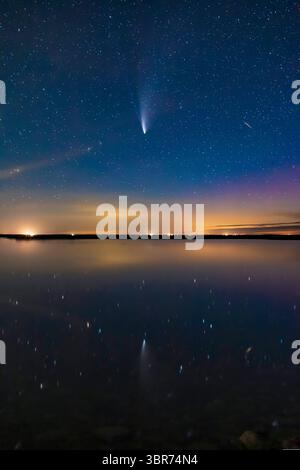 21 juillet 2020, Alberta, Canada : Comet NEOWISE (C/2020 F3) reflétée dans les eaux tranquilles cette nuit du lac Crawling dans le sud de l'Alberta. Une aurore sombre à droite colore le ciel en magenta. Le crépuscule persistant colore le bleu ciel. Un météore ou plus vraisemblablement un satellite en torche apparaît à droite et se reflète également dans l'eau. Même dans cette courte exposition, les deux queues â€” poussière et ion â€” sont visibles. C'était le 20 juillet 2020... le contenu principal de l'image est une exposition unique sans suivi de 25 secondes à f/2,8 et ISO 3200 avec l'objectif 35 mm Canon et le Canon 6D MkII. Les nuages lointains, l'horizon et l'eau dedans Banque D'Images