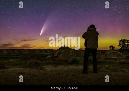 15 juillet 2020, Alberta, Canada : un selfie observant la comète NEOWISE (C/2020 F3) avec des jumelles dans la nuit sombre sans lune du 14 et 15 juillet 2020 du parc provincial Dinosaur, Alberta. Une faible aurore colore le ciel en vert et magenta. La queue ionique bleue pâle de la comète est visible en plus de sa queue de poussière plus brillante. Le sol est éclairé par la lumière des étoiles et la lumière des aurores seulement. ..C’est un mélange de 6 expositions empilées pour le sol (sauf moi) pour lisser le bruit, et une exposition pour le ciel et moi, toutes 13 secondes à f/2,5 avec l’objectif 35mm et Canon 6D MkII à ISO 6400. Topazs DeNoise ai appliqué Banque D'Images