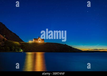 14 juillet 2020, Alberta, Canada : Comet NEOWISE (C/2020 F3) avec une petite exposition de nuages noctilucents au-dessus d'Emerald Bay et de l'emblématique hôtel Prince of Wales dans le parc national de Waterton Lakes, Alberta, à l'aube du 14 juillet 2020. C'était du nouveau point de vue du Parc International de la paix près de la marina. Capella est en haut à droite. ..il s'agit d'un mélange d'une pile de quatre expositions pour le sol et l'eau pour lisser le bruit, mélangé avec une seule exposition courte pour le ciel, toutes les 20 secondes à f/2,5 et ISO 400, plus une exposition courte supplémentaire de 8 secondes à ISO 100 mélangée avec un masque de luminosité pour réduire th Banque D'Images