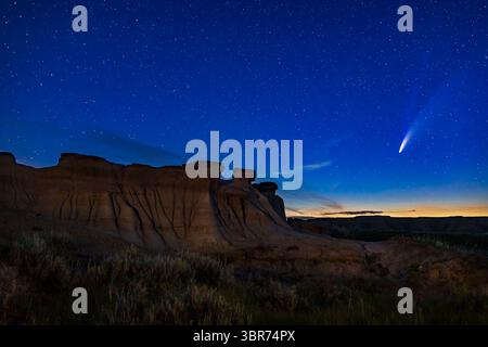 14 juillet 2020, Alberta, Canada : Comet NEOWISE (C/2020 F3) au-dessus de certaines formations érodées de hoodoo au parc provincial Dinosaur, Alberta, 14-15 juillet 2020. Le crépuscule colore le ciel. Dans ce cas, le premier plan est légèrement clair peint avec une lumière LED chaude. C'était du site Trail of the Fossil Hunters. ..il s'agit d'un empilement de 6 expositions pour le sol (expositions de 2 et 5 minutes à ISO 400 et f/8 pour la profondeur de champ) pour lisser le bruit, mélangées à une seule exposition non suivie de 20 secondes du ciel à f/2,8 et ISO 1600, le tout avec l'objectif Canon 35mm et l'appareil photo Canon 6D MkII. Une partie de la longue exp Banque D'Images