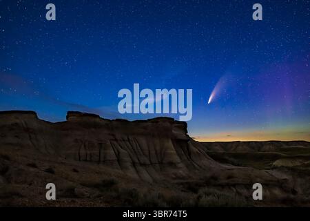 15 juillet 2020, Alberta, Canada : Comet NEOWISE (C/2020 F3) au-dessus de certaines formations érodées de hoodoo au parc provincial Dinosaur, Alberta, 14-15 juillet 2020. Une faible aurore est à droite. Le premier plan est éclairé par la lumière des étoiles seulement ; il n'y avait pas de peinture lumineuse employée ici. ..il s'agit d'un empilement de 12 expositions pour le sol pour lisser le bruit, mélangé avec une seule exposition non suivie du ciel, le tout à 20 secondes à f/2,8 et ISO 1600, le tout avec l'objectif Canon 35mm et l'appareil photo Canon 6D MkII. Prendre beaucoup de photos et les empiler a permis d'éclaircir le premier plan sans introduire trop de bruit an Banque D'Images