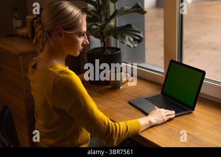 jeune femme dans un pull jaune mettant ses cheveux dans un chignon Banque D'Images
