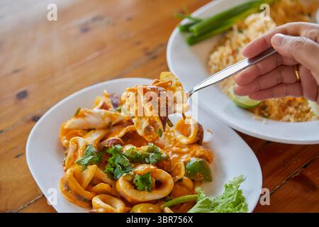 Coupe à la main de calmar sauté avec poudre de curry dans une assiette Banque D'Images