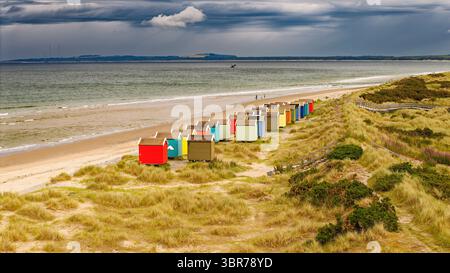 Findhorn Moray Coast Scotland cabanes de plage colorées sous un ciel tonnerre en été Banque D'Images