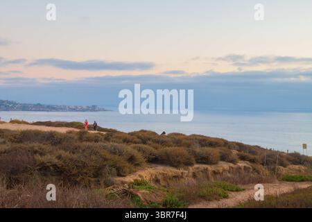 6 août 2020 : une femme portant une robe rose et un masque marche sur les falaises après le coucher du soleil au Torrey Pines Gliderport à la Jolla, Californie le jeudi 6 août 2020. (Crédit image : © Rishi Deka/ZUMA Wire) Banque D'Images
