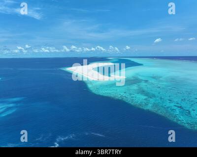 Vue aérienne du sable blanc d'une île artificielle rencontrant le lagon turquoise sous un vaste ciel bleu, Gulhi, atoll de Kaafu, Maldives. Banque D'Images
