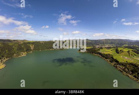 Vue aérienne de la paisible Lagoa das Furnas reflétant le ciel, embrassée par des collines verdoyantes et une végétation luxuriante, un panorama tranquille de l'art de la nature, Banque D'Images