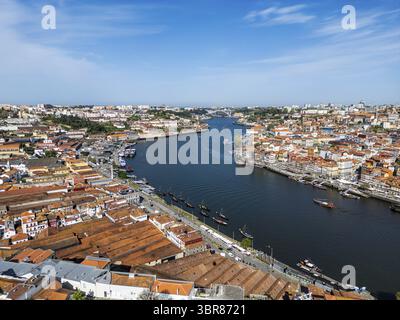 Vue aérienne des toits en terre cuite en cascade vers le fleuve Douro, reflétant le ciel Azur ci-dessus, créant un contraste saisissant à Porto, dans le district de Porto, au Portugal. Banque D'Images