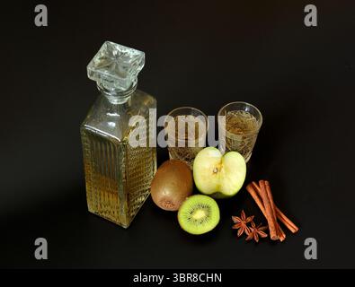 Liqueur de fruits de pomme verte et kiwi avec cannelle et anis sur fond noir. Gros plan. Banque D'Images