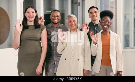 Groupe de personnes diverses souriant et agitant dans un cadre de bureau professionnel Banque D'Images
