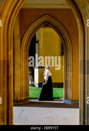Une femme en vêtements d'époque se tient dans un couloir voûté. Banque D'Images