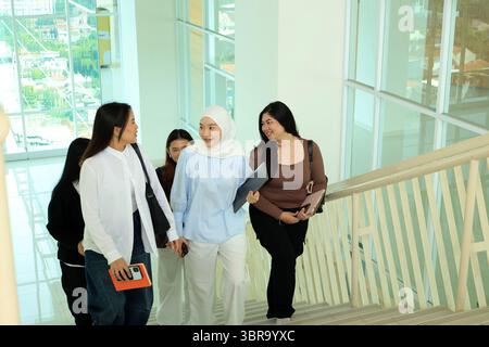 Cinq camarades de classe Asian College Student marchant sur les escaliers du Campuss tout en discutant Banque D'Images
