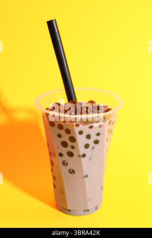 Thé à bulles de lait savoureux en verre sur fond jaune Banque D'Images