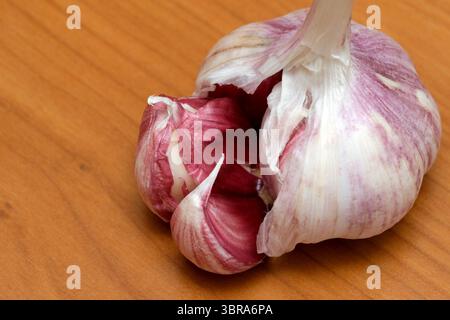 Un bulbe d'ail à la peau violette repose sur un comptoir en bois, prêt pour la cuisson. Banque D'Images
