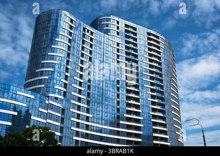 Une magnifique façade en verre met en valeur un design contemporain contre les nuages moelleux. Banque D'Images