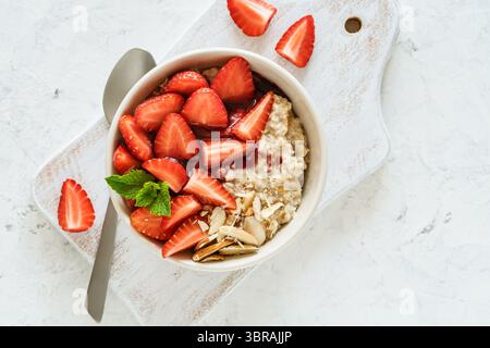 Bol d'avoine multigrain avec fraises fraîches, confiture de baies et noix. Porridge sain pour le petit déjeuner, vue panoramique Banque D'Images