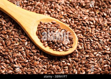Graines de lin sur cuillère en bois ou graines de lin comme fond, graines de lin brunes de près. Alimentation saine. Produit biologique. Banque D'Images