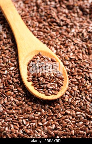 Graines de lin sur cuillère en bois ou graines de lin comme fond, graines de lin brunes de près. Alimentation saine. Produit biologique. Banque D'Images