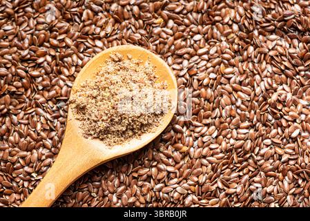 Graines de lin comme fond et sol de graines de lin sur cuillère en bois, vue de dessus, espace de copie. Ingrédient alimentaire sain, superaliment. Produit biologique. Banque D'Images