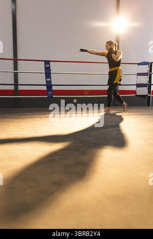 Boxer féminin portant un haut sans manches noir et des enveloppements de main Jabbing dans un ring de boxe, espace copie Banque D'Images
