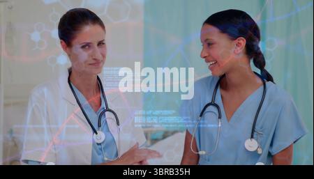 Analyse de deux médecins portant des gommages et une blouse de laboratoire examinant les graphiques ADN dans la salle d'examen, stéthoscopes Banque D'Images