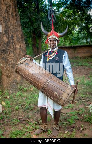 Portant une coiffe en corne de bison et jouant du tambour du tronc d'arbre creusé, un membre de la tribu Maria Gond dans le Chhattisgarh, Inde, Asie Banque D'Images