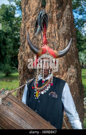 Portant une coiffe en corne de bison et jouant du tambour du tronc d'arbre creusé, un membre de la tribu Maria Gond dans le Chhattisgarh, Inde, Asie Banque D'Images