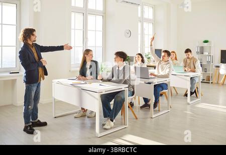 Leçon d'école, professeur masculin demandant à de jeunes étudiants amis de collège, brainstorming de travail Banque D'Images