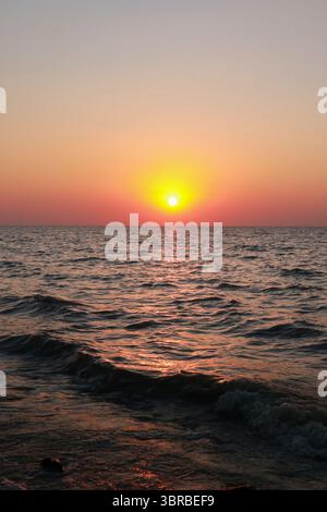 Superbe coucher de soleil sur l'océan avec des vagues douces et un ciel coloré illuminé par la lumière du soir Banque D'Images