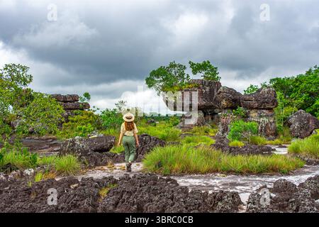 Un voyageur se promène à travers de superbes formations rocheuses à Guaviare, en Colombie, entouré d'une végétation luxuriante et d'un ciel spectaculaire. Banque D'Images